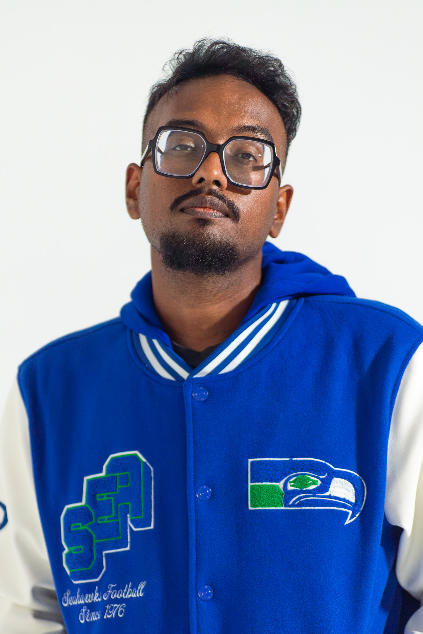 Wearing a Seahawks varsity jacket against a white backdrop