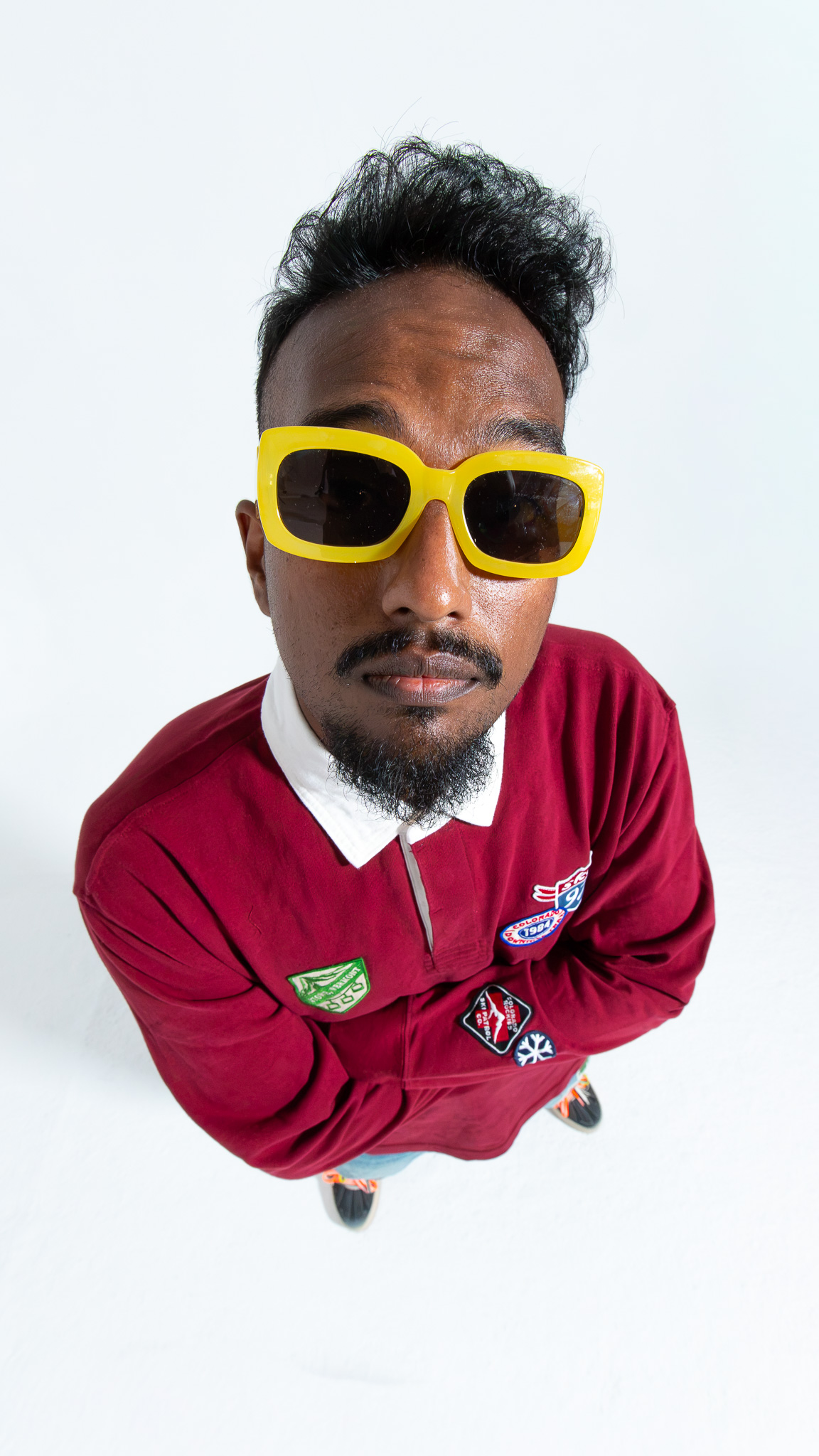 Overhead portrait wearing yellow sunglasses and a red rugby shirt